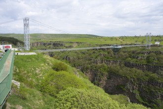 Wide landscape with modern bridge over green, rocky gorge under cloudy sky, Diamond Bridge, Diamond