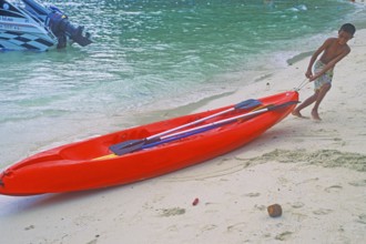 Boy pulls a kayak on the beach of Ko Phi Phi Don, two years in front of the tsunami, Thailand,