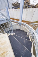Downward spiral of steel and concrete staircase, showing modern building style, parking garage