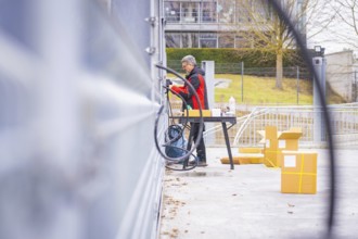 Person working in the area with cables and boxes, building in the background, parking garage