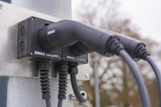 Two electronic chargers with cables on a metal bracket, parking garage construction with charging