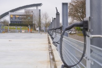 Row of charging stations with a modern building in the background, parking garage construction with