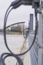 View of a building with solar panels and charging cable in the foreground, parking garage