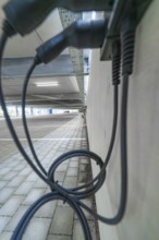 Charging cables hang on a concrete wall under ceiling in a parking garage, parking garage