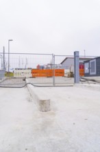 View of a cordoned off construction site with concrete floors and fences, parking garage