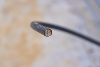 Close-up of a cut cable with visible wires, parking garage construction with charging