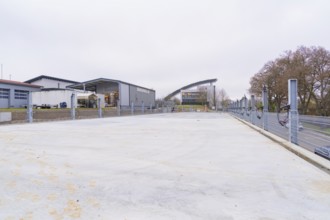 Industrial building in cloudy weather with an empty parking lot in the foreground, parking garage