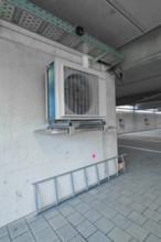 Air conditioning system placed on a concrete wall and a ladder in a parking garage, parking garage
