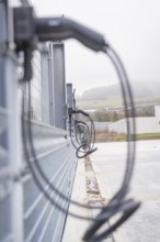 Cables run along a fence in an industrial environment, with foggy weather, parking garage