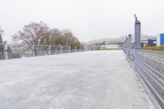 Empty parking lot with mesh fence on a foggy day in an industrial area, parking garage construction