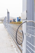 Electrical cable in front of a grey fence in an industrial area, parking garage construction with