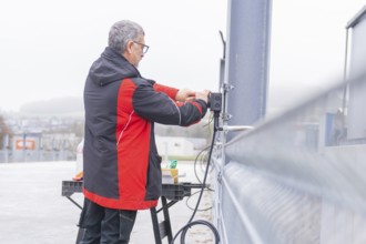 Person installing electrical cables in an industrial environment, parking garage construction with