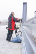 Man working on electrical cable installation in open area, parking garage construction with