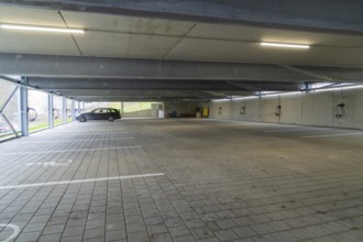 Empty parking garage with marked parking spaces and lighting, parking garage construction with