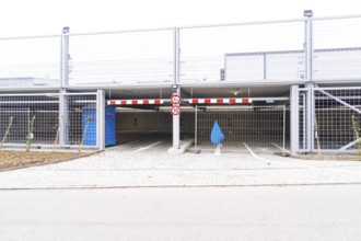 An empty parking deck with a barrier and a traffic sign. The area is secured by fences, car park