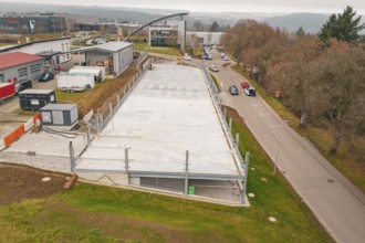 Aerial view of a parking lot next to a street in an urban environment, parking garage construction