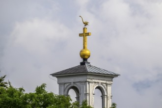 Ödeshög church tower with golden cross and weather swan Swan rising into the sky, near Tåkern,