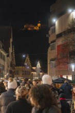Nighttime scene with crowd and illuminated castle in the background, Weihnachtsmark Nagold,