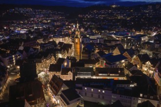 Nocturnal aerial view of a city with an illuminated church and illuminated buildings,