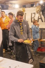 Person preparing waffles at a stand at a market at night, Weihnachtsmark Nagold, LandkreiScalw,