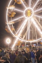 An illuminated Ferris wheel lights up the night above a busy Christmas market, Weihnachtsmark