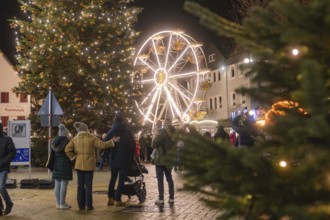 People enjoy the Christmas atmosphere with tree and Ferris wheel at night, Weihnachtsmark Nagold,