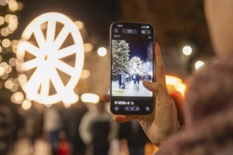 A Ferris wheel and a tree at a Christmas market are photographed with a smartphone, Weihnachtsmark