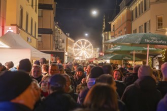 Busy night market with illuminated Ferris wheel in urban surroundings, Weihnachtsmark Nagold,