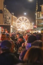 Night market with crowd and glowing Ferris wheel in the background, Weihnachtsmark Nagold,