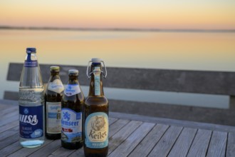 Various drinks bottles on a wooden table at Dümmersee at sunset, Lembruch, Lower Saxony, Germany