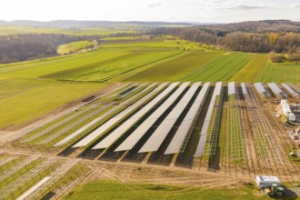 Solar panels are lined up along fields in a green, vast landscape, energy revolution, construction