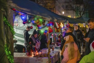 Colourful and festively decorated stands at a Christmas market with many visitors, Christmas