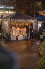 Atmospheric Christmas market stand with winter decorations and visitors at night, Christmas market,