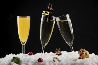 Three champagne glasses with lucky charms for New Year in the snow
