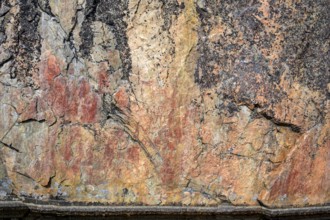 Prehistoric rock art in reddish brown on a textured surface Rock paintings of Värikallio, rock wall