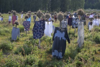 Artwork outdoor installation The silent people of Reijo Kela Straw dolls wear colorful clothes in a