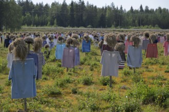 Artwork installation OUThe silent people of Reijo Kela Straw dolls wear colorful clothes in a field