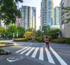 Canadian flag waving between modern buildings while a woman with backpack and helmet rides her