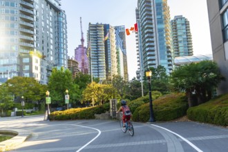 Woman in a helmet and backpack riding a bicycle on a paved path in vancouver, british columbia,