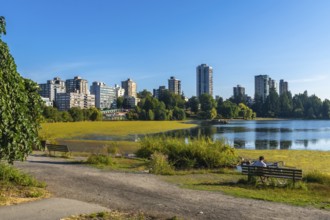 Vancouver city skyline reflecting on trout lake with yellow algae bloom during summer in british