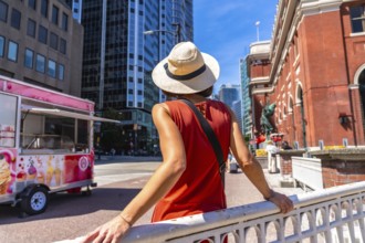 Young woman wearing a straw hat and an orange dress is enjoying the urban landscape of vancouver.