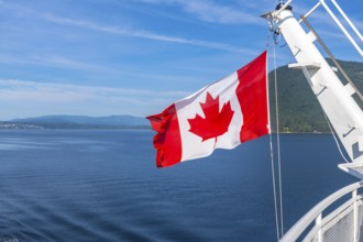 Canadian flag waving in the wind on a ferry sailing from victoria, vancouver island, to vancouver,