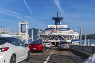 Cars are boarding a ferry with a canadian flag, departing from victoria on vancouver island to