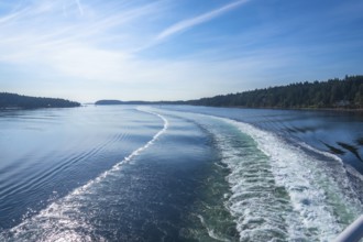 Churning white foam and turquoise water create a scenic wake as a ferry crosses the strait of