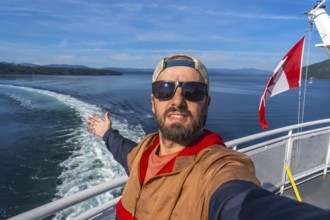 Tourist wearing sunglasses and a cap enjoys ferry trip from victoria, vancouver island, to