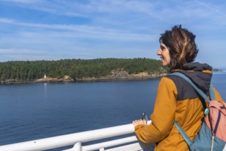 Tourist leaning on the ferry railing, enjoying breathtaking ocean views and a small island with a