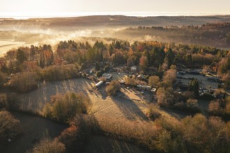 Foggy autumn landscape with village surrounded by trees and fields at sunrise, Gechingen, Calw
