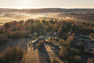 Snowy village surrounded by thick forests with fog and sunrise over the hills, Gechingen, Calw
