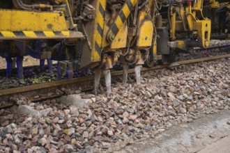 Detailed view of a track construction machine working on a layer of ballast, tamping machine on