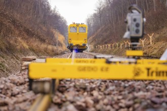 Yellow work machine on railroad track with surveyor in autumn environment, stuffing machine on